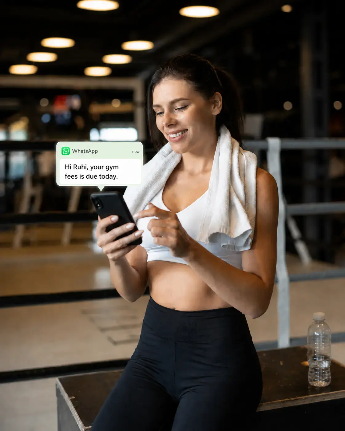 Gym member receiving a WhatsApp fee reminder on her phone